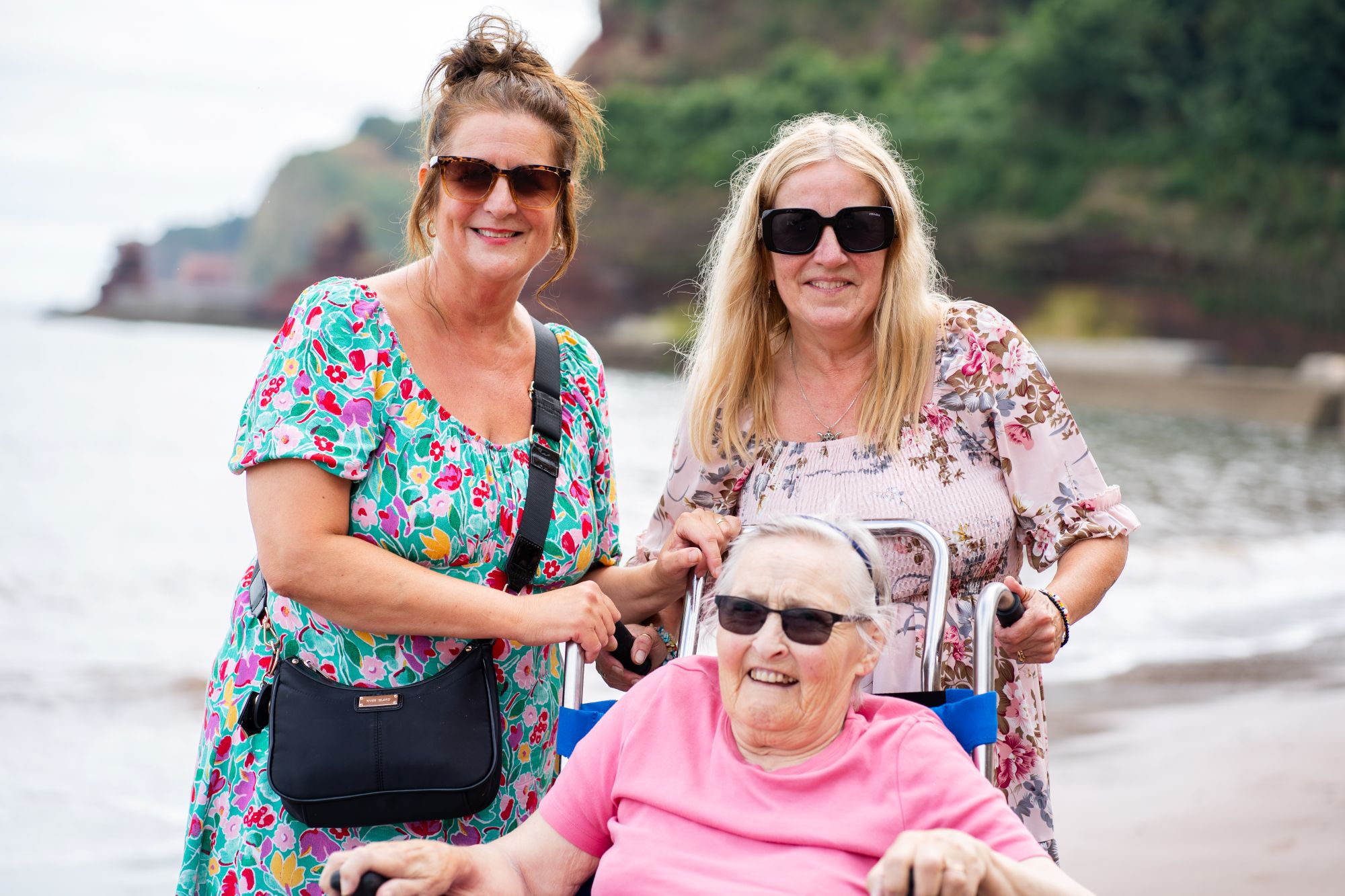 Julie-Yates-and-Lisa-Burge-from-the-Sefton-Hall-care-team-at-the-beach-in-Dawlish-with-resident-Shirley-Mapston who is in a beach wheelchair