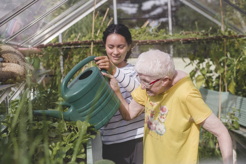 A resident helps water the plants in the greenhouse at The Old Rectory care home in Exeter.