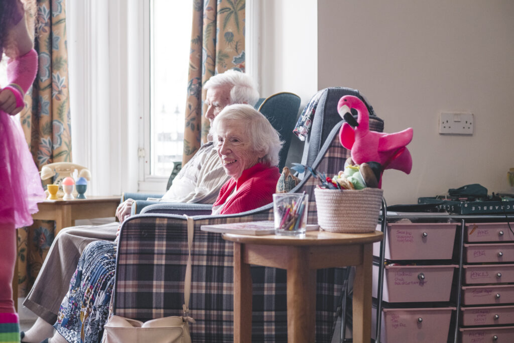 Two residents sitting in chairs in the lounge at Parkwood House care home. Photo is being used alongside an article about the social care crisis