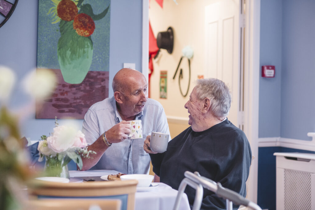 Andy, a carer at The Old Rectory care home in Exeter sits and chats with resident, Ron.