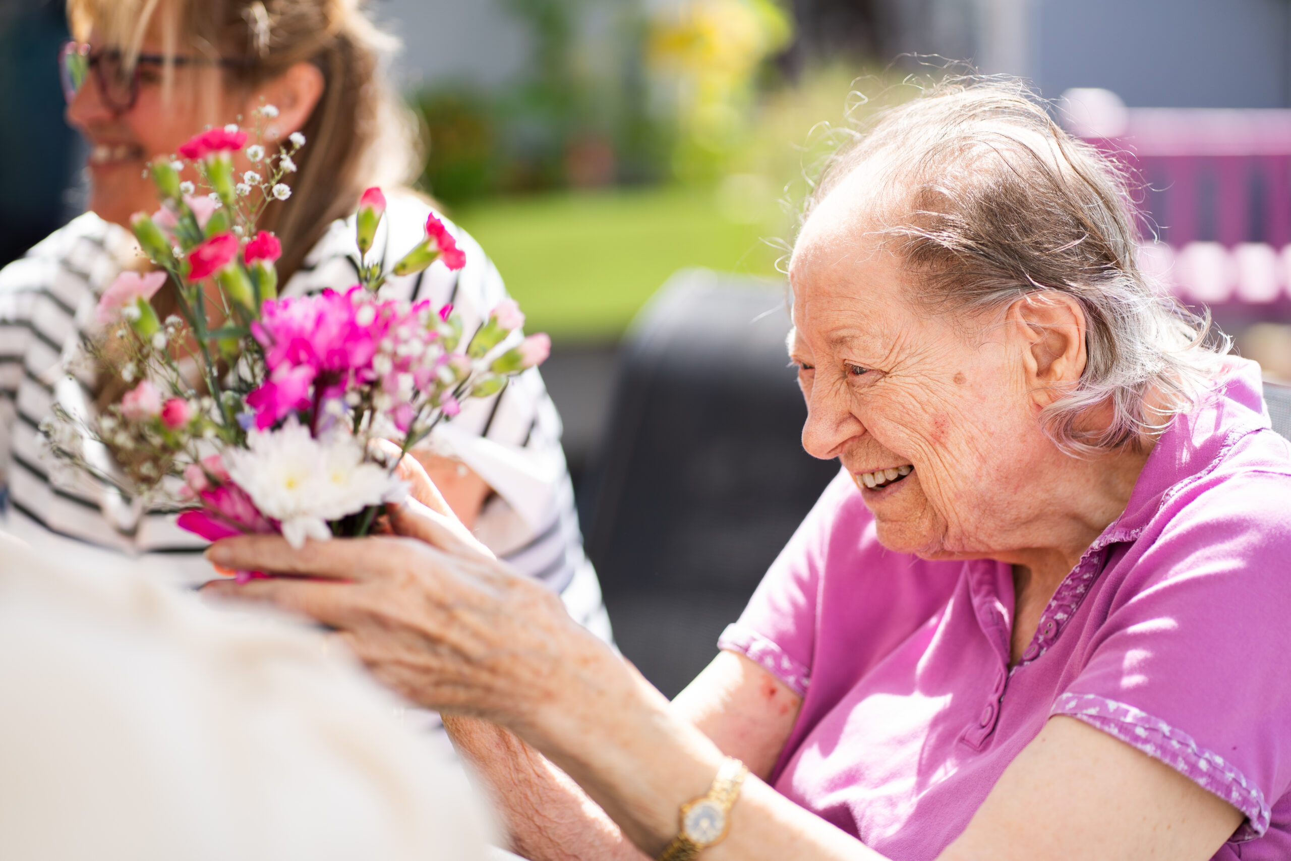 A care home resident enjoys some flower arranging in the sunshine