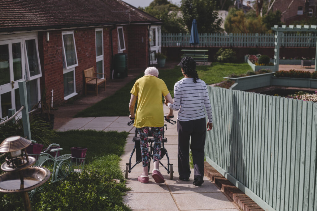 A resident at The Old Rectory takes a walk with a care team member in the gardens of the care home