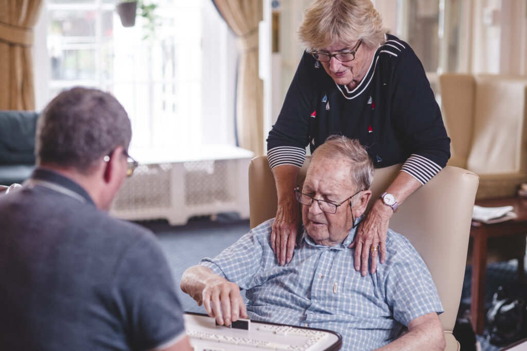 A Sefton Hall resident plays a game of dominoes with a family member
