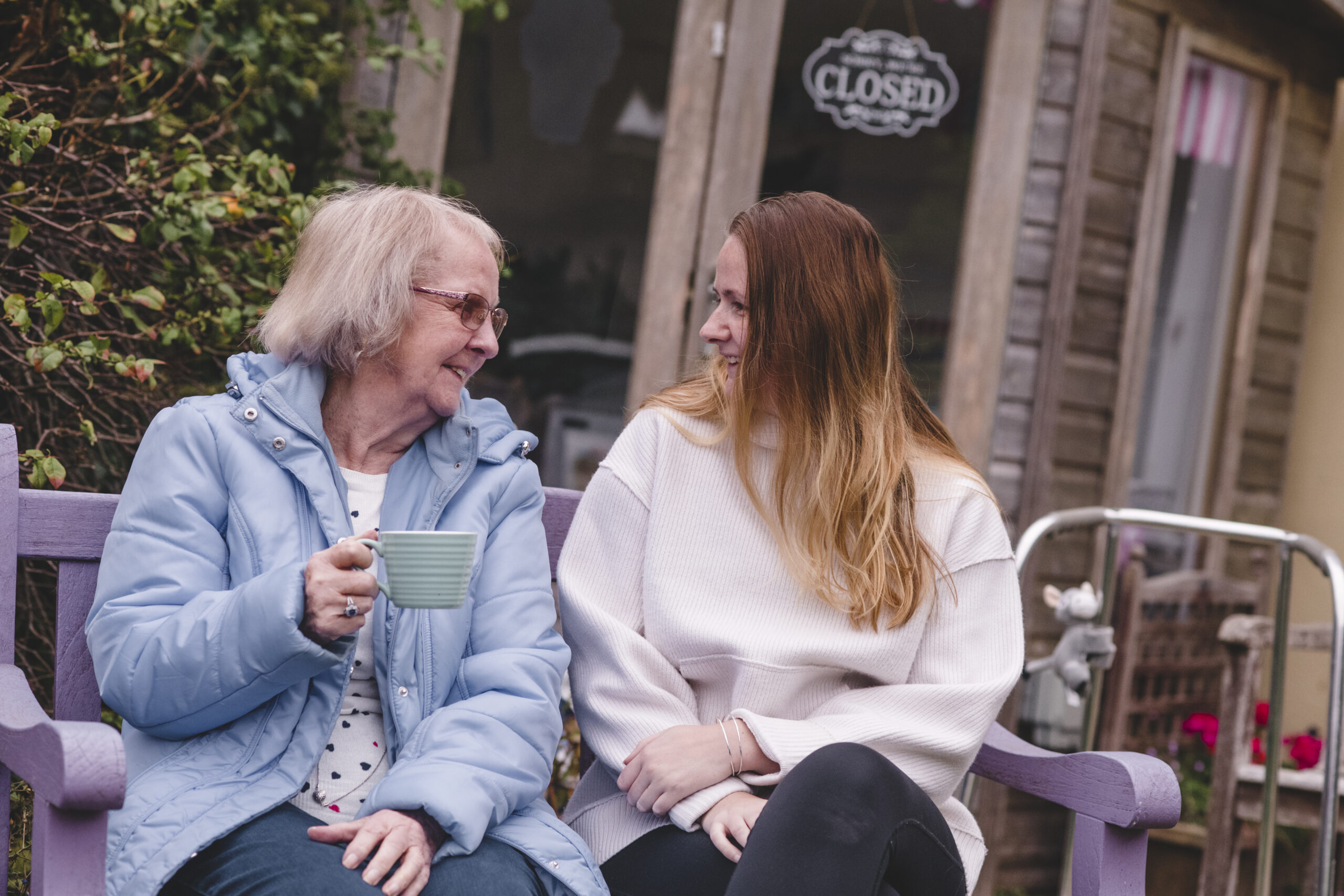 A resident at The Seaton enjoys a chat and a cup of team with a member of the care team in the garden.