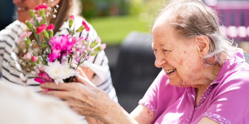 A care home resident enjoys some flower arranging in the sunshine