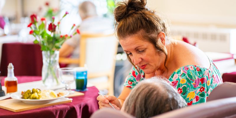 Sefton-Hall-care-team-member-Julie-Yates-helps-a-resident-eat-lunch