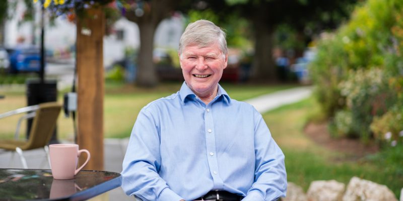 Southern Healthcare's managing director Geoffrey Cox sitting in a chair in the garden at Sefton Hall care home in Dawlish